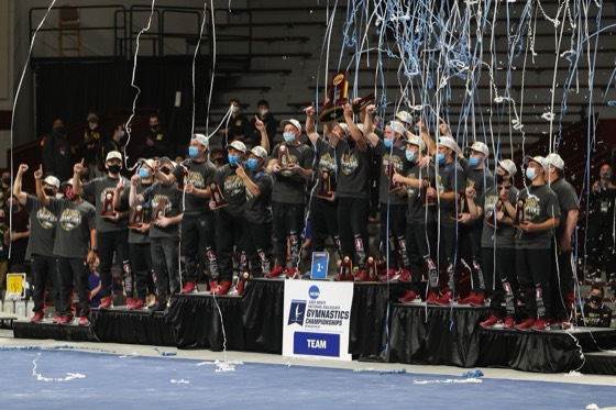 Stanford gymnastics holding a championship banner during a confetti celebration